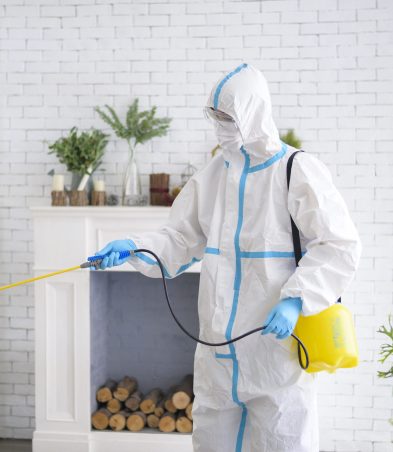 A medical staff in PPE suit is using disinfectant spray in living room, Covid-19 protection , disinfection concept