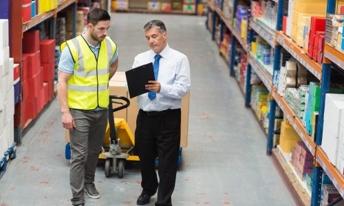 Warehouse worker talking with his manager in a large warehouse